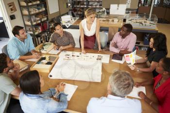 Female Boss Leading Meeting Of Architects Sitting At Table
