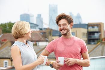 Young Couple Relaxing With Coffee On Roof Terrace