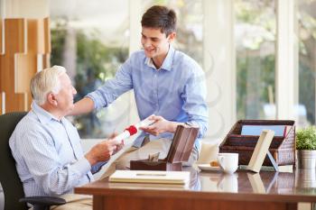Grandfather Showing Document To Teenage Grandson