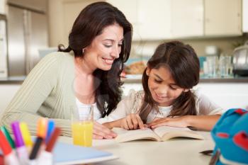 Mother Helping Daughter With Reading Homework At Table