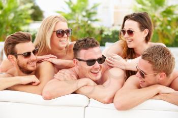 Group Of Young People On Holiday Relaxing By Swimming Pool