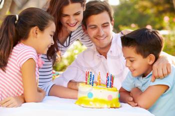 Family Celebrating Birthday Outdoors With Cake