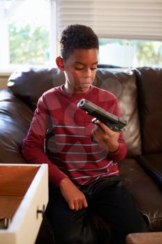 Boy Playing With Parent's Gun He Has Found At Home