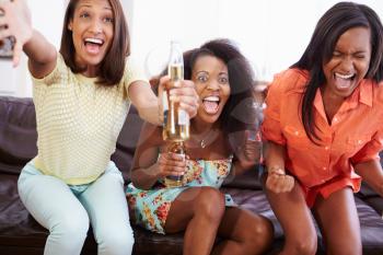 Group Of Women Sitting On Sofa Watching TV Together