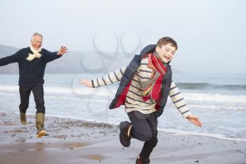 Grandfather And Grandson Running On Winter Beach