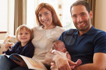 Family Sitting On Sofa With Newborn Baby