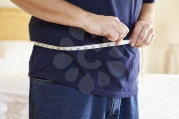 Close Up Of Overweight Man Measuring Waist