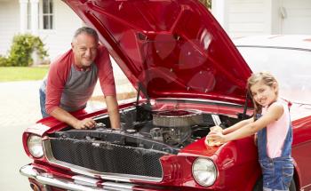 Grandfather And Granddaughter Working On Classic Car