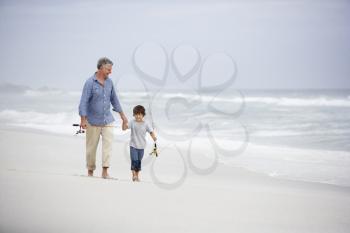 Senior man and grandson walking on beach