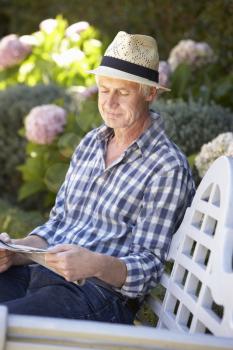 Mid age man reading newspaper in garden