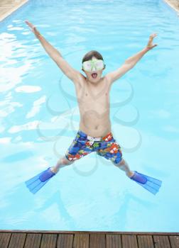 Boy jumping into outdoor swimming pool