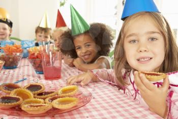 Young children eating jam tarts at birthday party