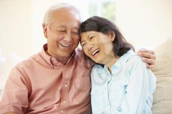 Senior Asian Couple Sitting On Sofa At Home Together