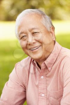 Portrait Of Smiling Senior Asian Man Sitting In Park