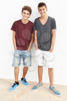 Portrait Of Two Hispanic Teenage Boys Leaning Against Wall