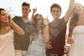 Group Of Teenage Friends Dancing Outdoors Against Sun