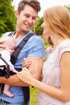 Parents With Baby In Carrier On Walk In Countryside