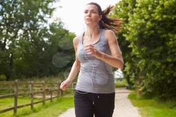 Woman Running In Countryside Wearing Earphones