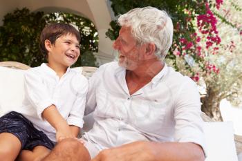 Grandfather At Home Sitting On Outdoor Seat With Grandson