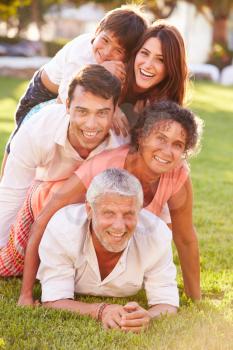 Multi Generation Family Lying In Pile Up On Grass Together