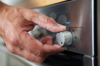 Close Up Of Hand Setting Temperature Control On Oven