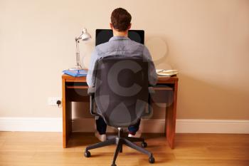 Man Sitting At Desk Working At Computer In Home Office