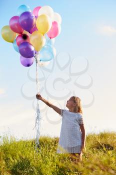 Young Girl Holding Bunch Of Colorful Balloons Outdoors