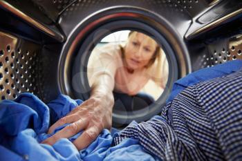 Woman Doing Laundry Reaching Inside Washing Machine