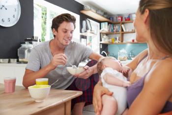 Family With Newborn Baby Daughter At Breakfast Table