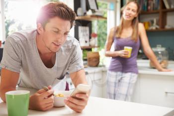 Couple Eating Breakfast Whilst Checking Mobile Phone