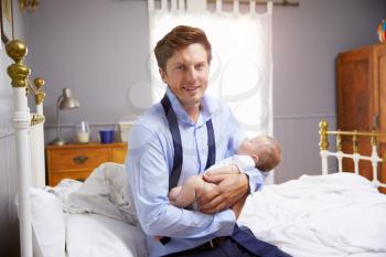 Father Dressed For Work Holding Baby In Bedroom