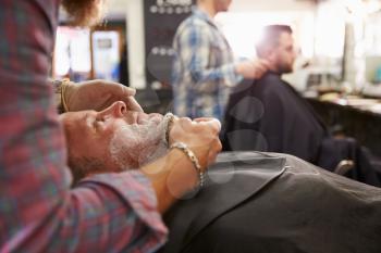 Male Barber Preparing Client For Shave In Shop