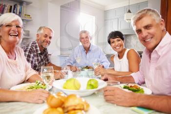 Portrait Of Mature Friends Enjoying Meal At Home Together