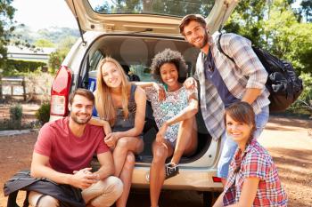 Group Of Friends On Trip Sitting In Trunk Of Car