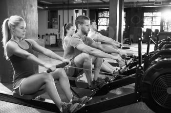 Black And White Shot Of Gym Class Using Rowing Machines