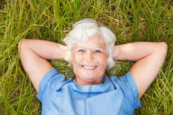 Senior woman lying on grass relaxing