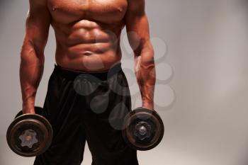 Male bodybuilder working out with heavy dumbbells, with copy space