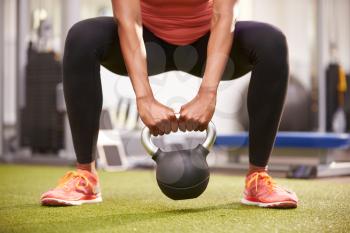 Woman exercising with a kettlebell weight, front view low-section crop