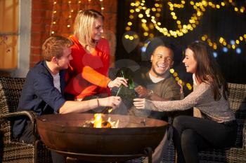 Group Of Friends Enjoying Evening Drinks By Firepit