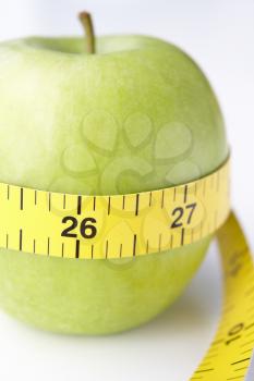 Green apple with tape measure wrapped around
