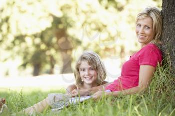 Mother And Daughter Sketching In Countryside Leaning Against Tree