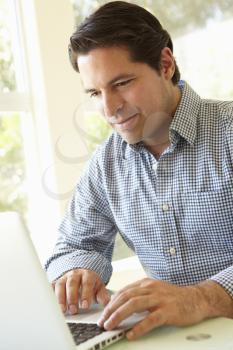 Hispanic Man Using Laptop In Home Office