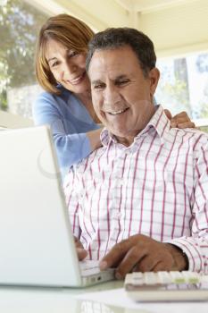 Senior Hispanic Couple Using Laptop In Home Office