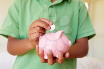 Young boy putting money in piggybank