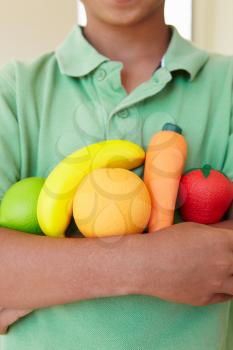 Young boy holding plastic fruit and vegetables