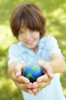 Young Boy Playing Holding Model Of Globe In Park