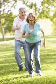 Senior Hispanic Couple Running In Park