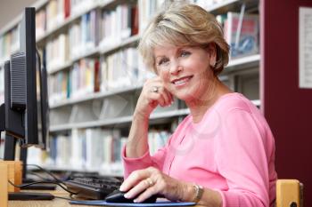 Senior woman working on computer in library