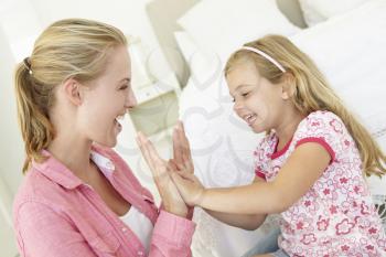 Mother And Daughter Playing Together In Bedroom