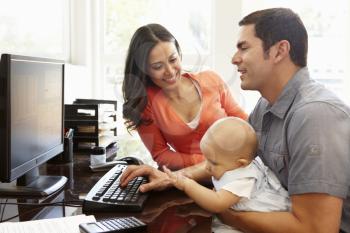 Hispanic couple and baby in home office